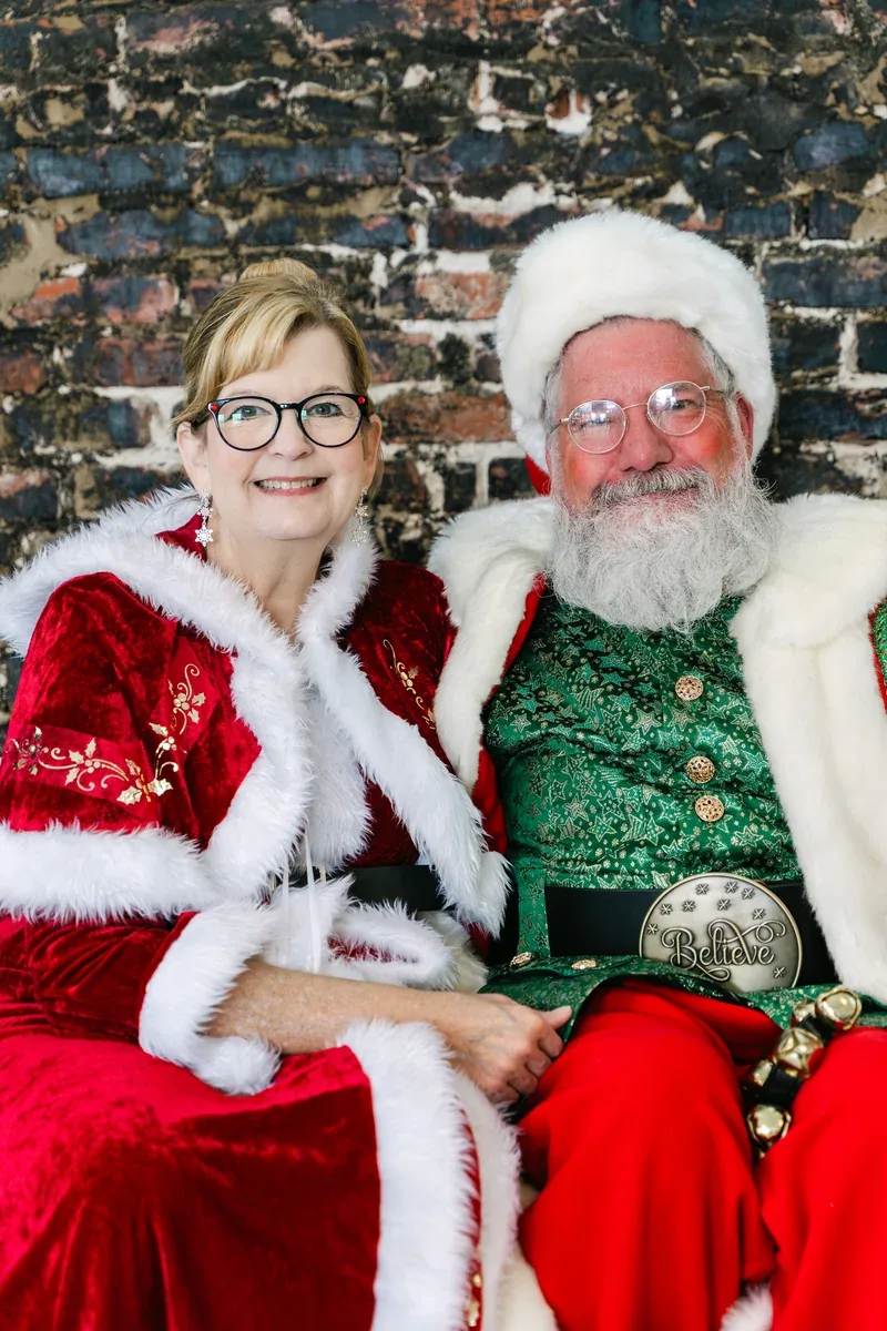 Santa Michael and Mrs. Claus sit together in their red and white Christmas outfits.
